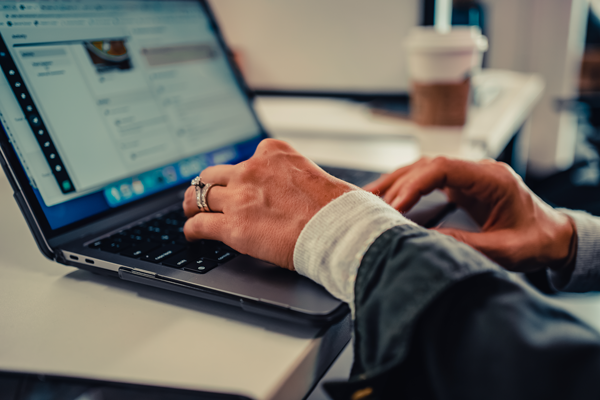 A woman's hands typing on a laptop.