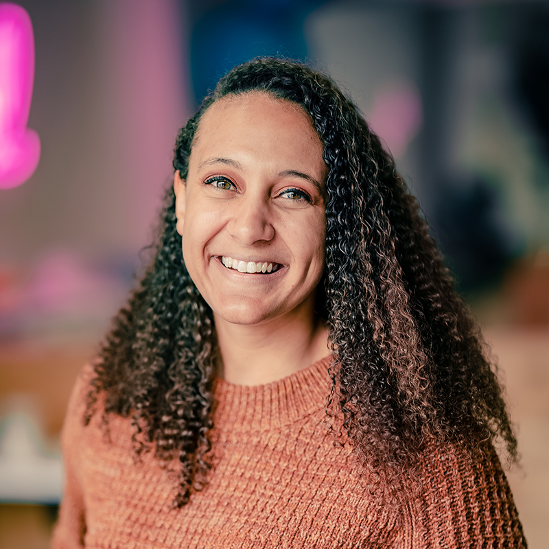 Headshot of smiling woman in front of a colorful background.